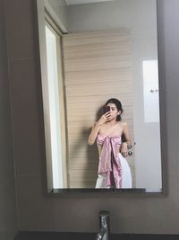 Reflection of woman taking selfie in mirror