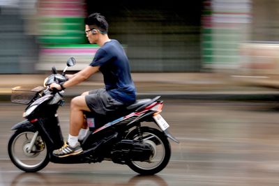 Side view of man riding motorcycle on road