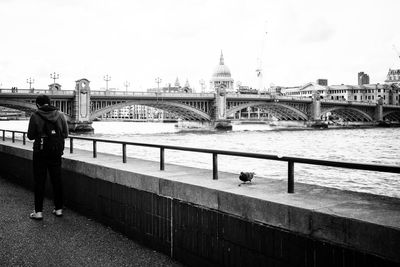 Rear view of man standing on promenade against southwark bridge over thames river