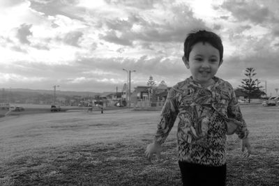 Portrait of boy standing on field against sky