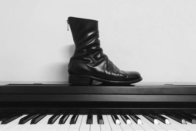 Low section of man playing piano against wall at home