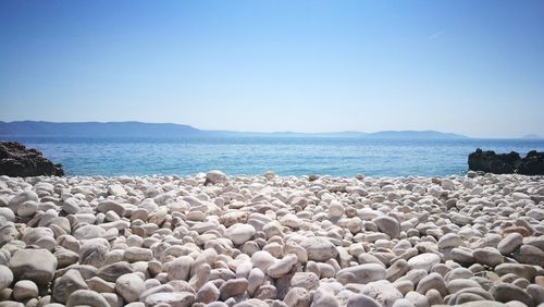 Rocks on beach against clear blue sky