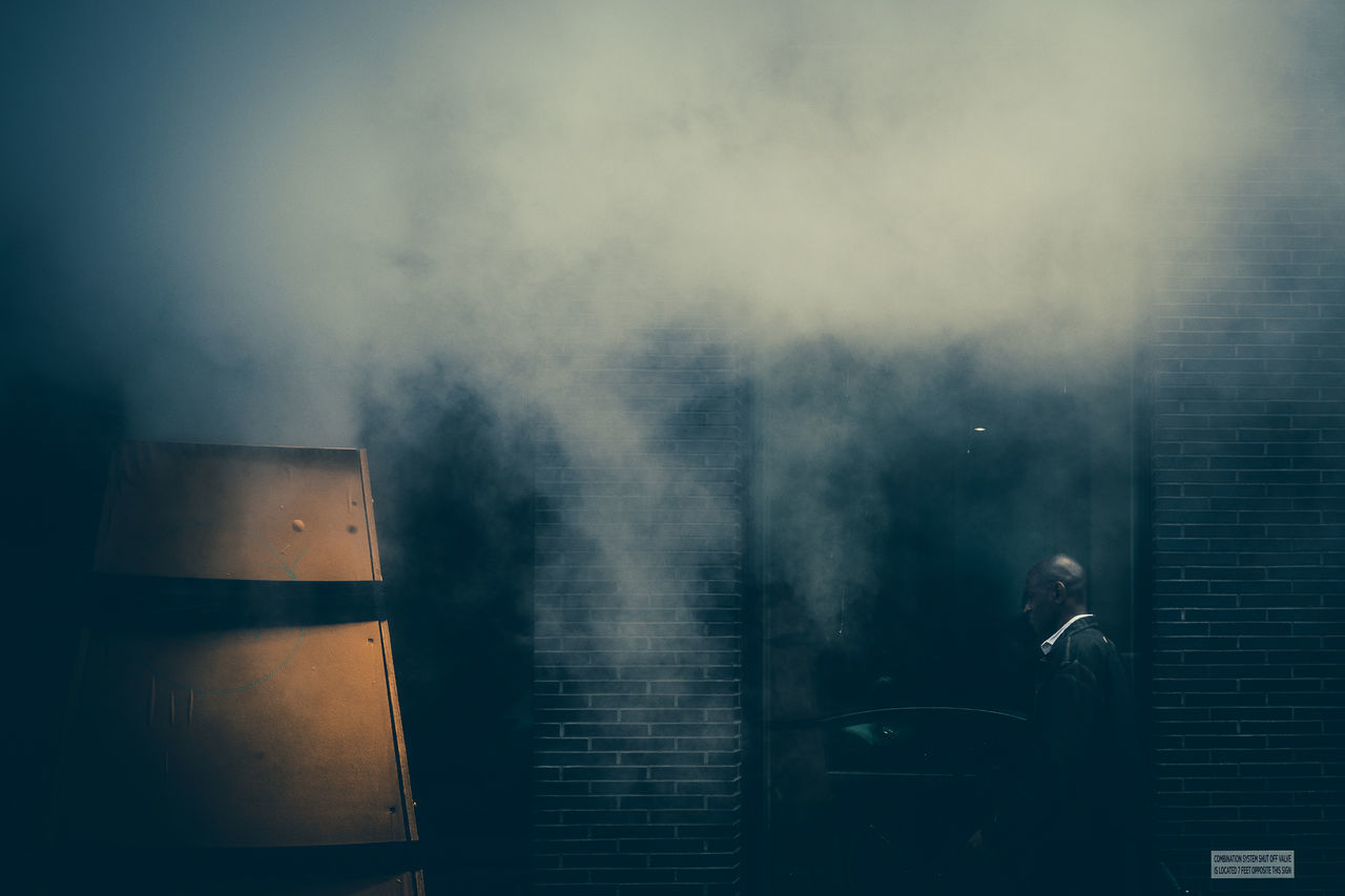 one person, real people, men, building exterior, architecture, smoke - physical structure, built structure, business, adult, suit, lifestyles, businessman, standing, outdoors, business person, day, males, well-dressed, side view