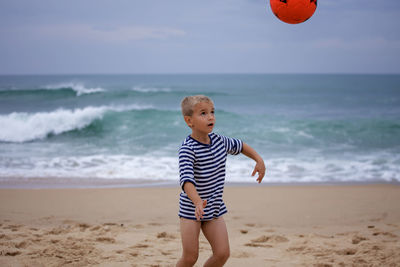 Young soccer player plays barefoot on the ocean shore. football, sport, passion. active lifestyle