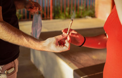 Midsection of man holding red while standing on table