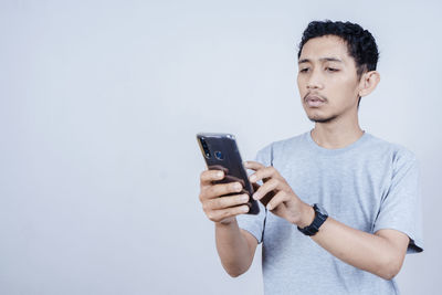 Young man using smart phone against white background