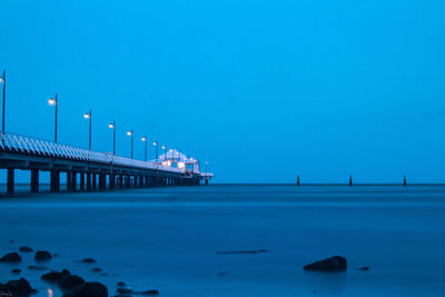 Pier over sea against clear blue sky