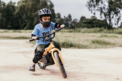 Portrait of boy riding push scooter on field