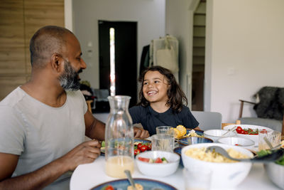 Happy boy having breakfast while sitting at dining table with father in home