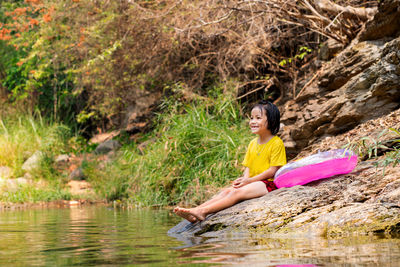 Cute girl sitting on rock by lake