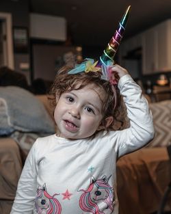 Portrait of cute girl wearing unicorn hat while standing at home
