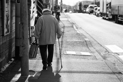 Rear view of senior woman walking on sidewalk