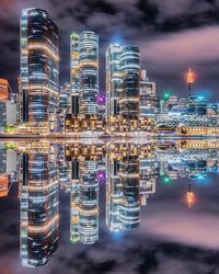 Reflection of illuminated modern buildings in city on river at night