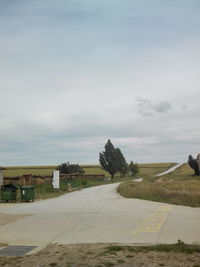 Road on field against cloudy sky