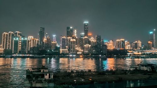 Illuminated buildings in city against sky at night