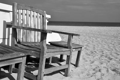 Empty chairs on beach against sky