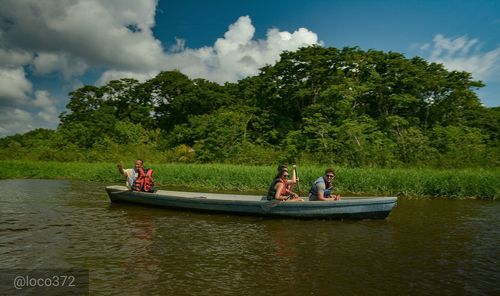 People in boat on lake against sky