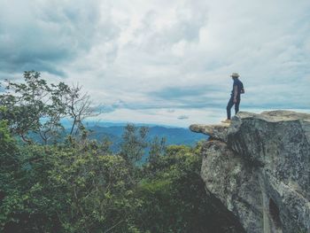 Rear view of man standing on rock against sky