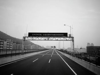 Road sign on highway against sky in city