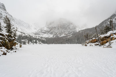 Snow covered land and mountains against sky