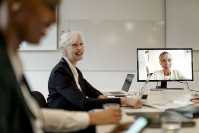 Smiling female manager discussing with colleagues through web conference during global business meeting