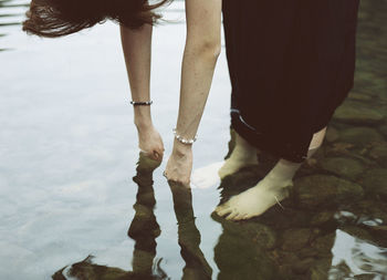 High angle view of woman touching shallow water on lakeshore