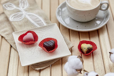 Aesthetic coffee time outside. cup of cappuccino and chocolate sweets hearts. romantic date