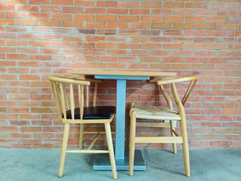 Empty chairs against brick wall