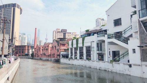 Wet street amidst buildings in city against sky