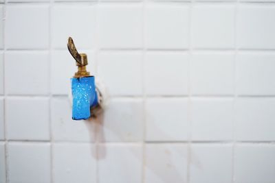 Close-up of blue faucet on tiled wall