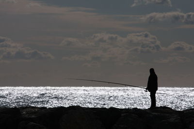 Side view of silhouette man fishing in sea
