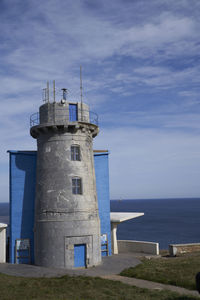 Lighthouse by sea against sky