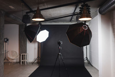 Interior of modern photo studio with octaboxes and professional photo camera on tripod against black background