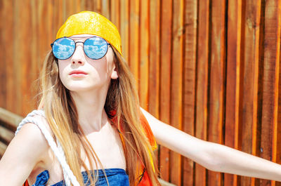 Girl wearing sunglasses against wall