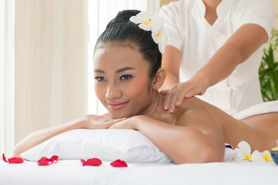 Smiling young woman being massaged by massage therapist in spa