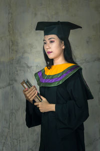 Portrait of a smiling young woman standing against wall