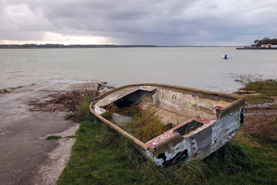 Abandoned boat at shore against sky