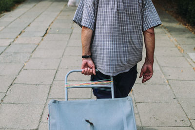 Man holding umbrella walking on sidewalk