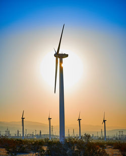 Traditional windmill on landscape against sky during sunset