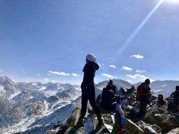 Young woman standing on mountain against blue sky during winter