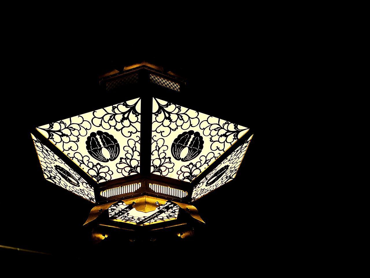 LOW ANGLE VIEW OF ILLUMINATED ELECTRIC LAMP AGAINST BLACK BACKGROUND