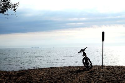 Man riding bicycle on beach against sky