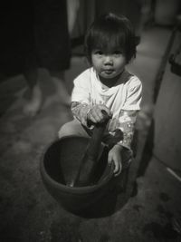 Portrait of cute girl holding mortar and pestle on floor at home