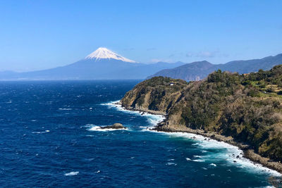 Scenic view of sea and mountains against clear blue sky