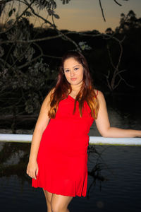 Portrait of young woman standing by railing