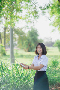 Smiling young woman holding flaming torch while standing at park