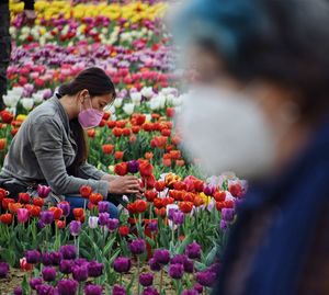 Low section of woman standing by flowering plants