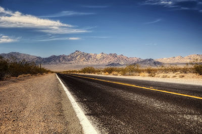 Road leading towards mountains against sky