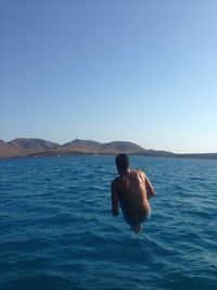 Man surfing in sea against clear sky