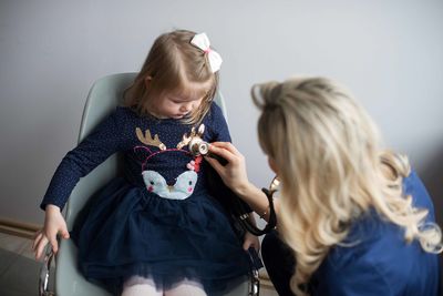 Pediatrician examining cute girl in medical clinic